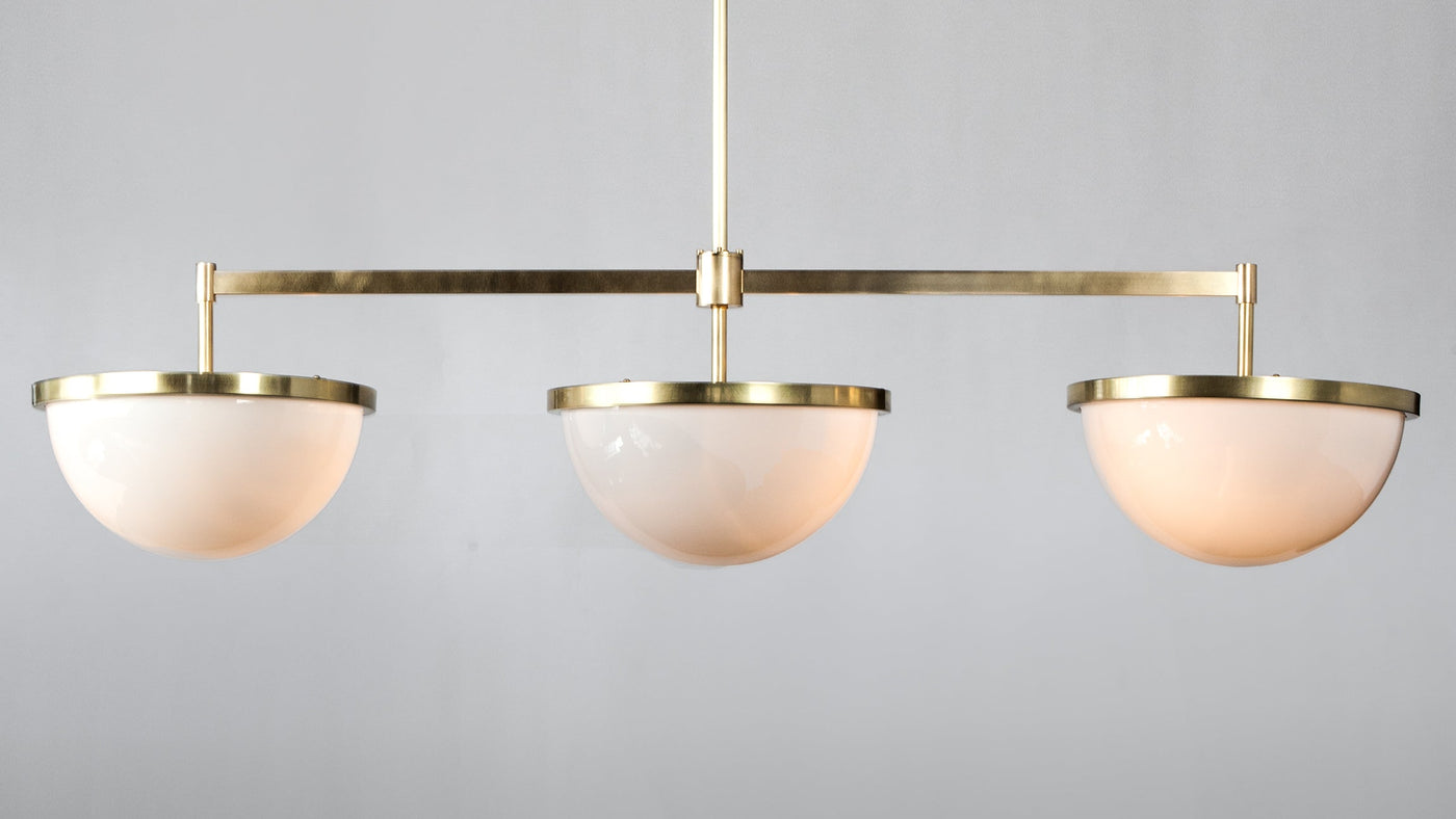 A detail shot of the Nevins 14 Billiard Light in Burnished Brass, designed by Alan Wanzenberg for Remains Lighting Co., hanging lit in the photo studio at the Remains factory in Brooklyn, New York.