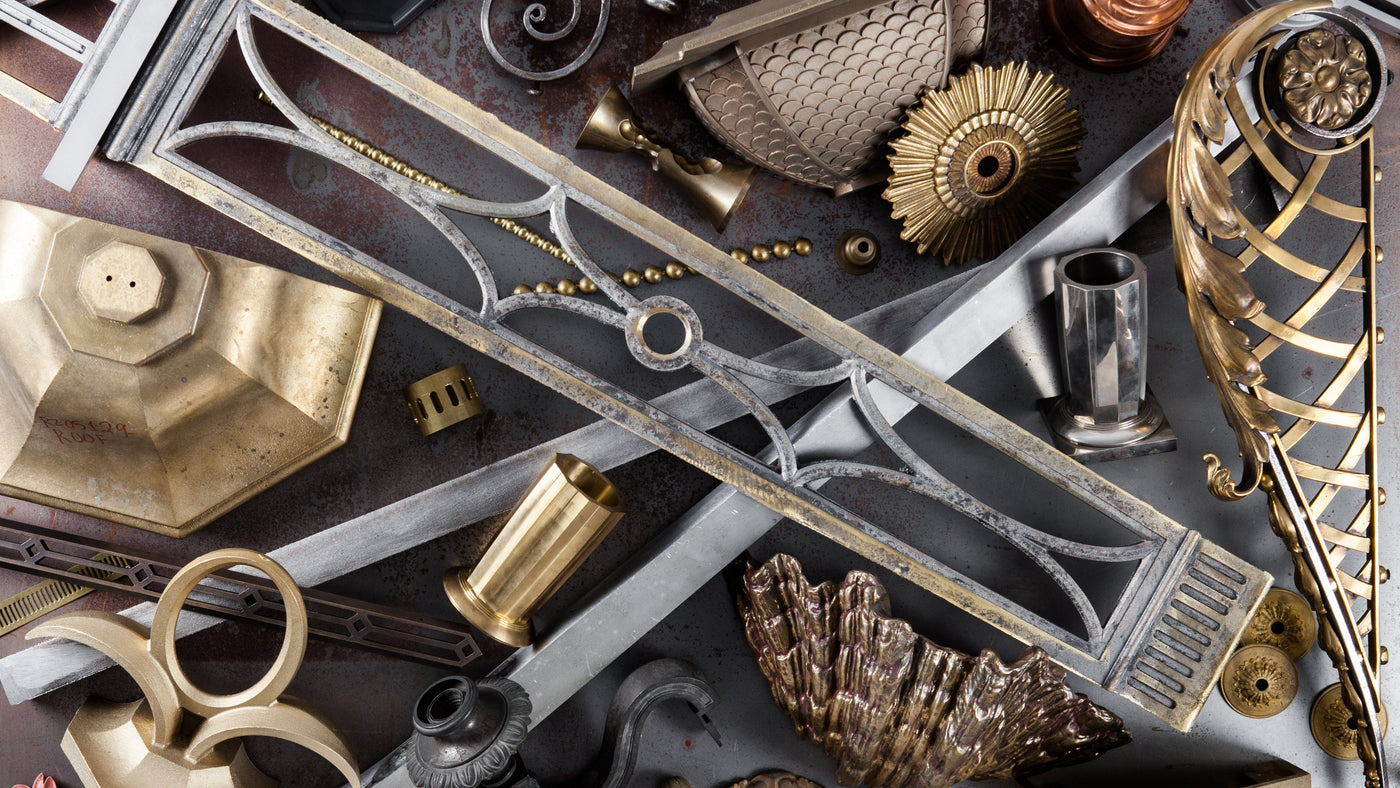 A table spread with brass, bronze, iron, and nickel light fixture parts