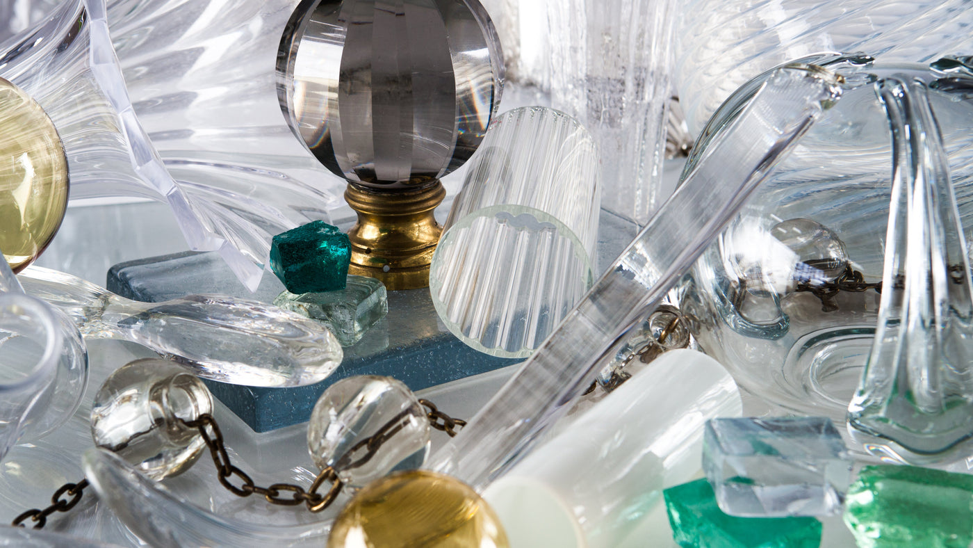 a table spread with cast glass, colored glass, crystal, white glass, and more