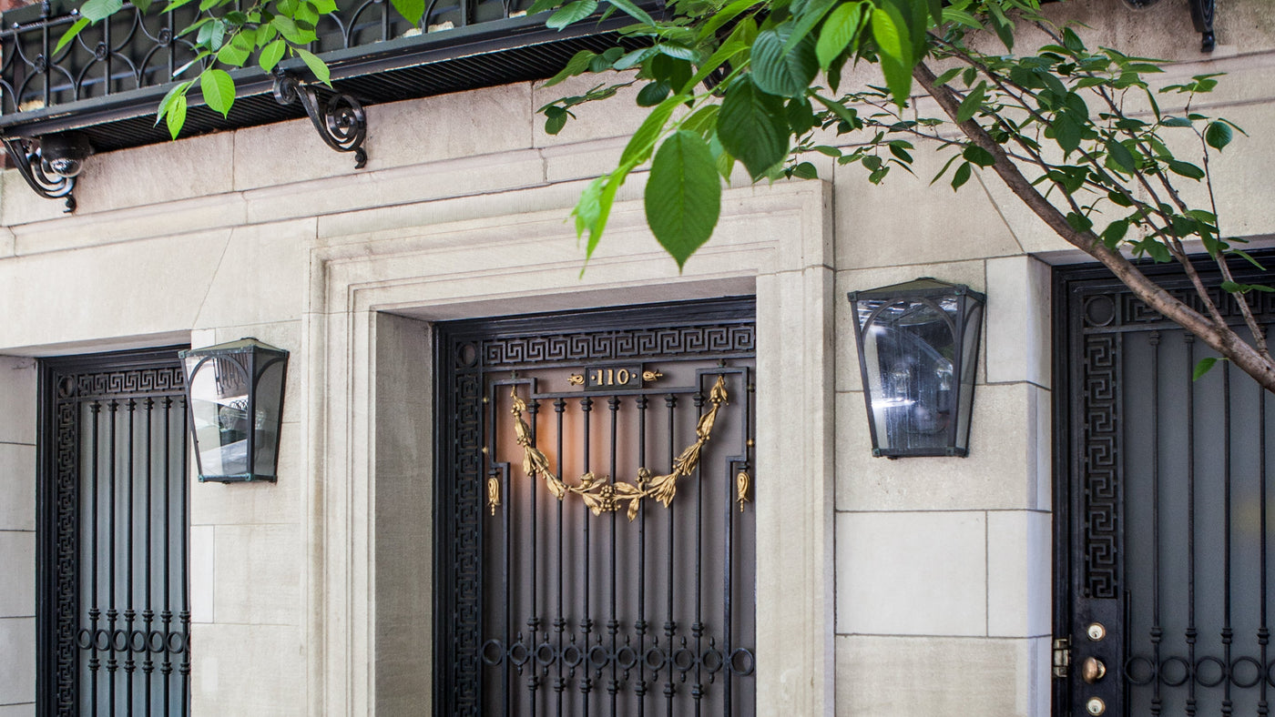 A pair of dark waxed bronze turned verdigris Mercer 17 Sconces flanks the doorway of a limestone town house in Manhattan's Upper East Side.