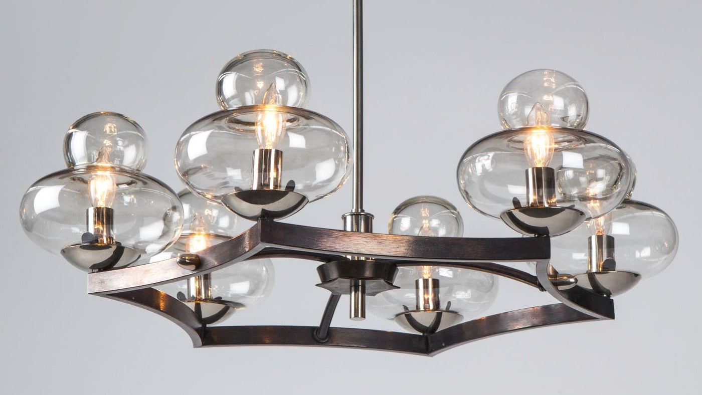 Detail view of a six light chandelier with clear bubble glass shades arrayed at the points of a blackened metal star form body. 