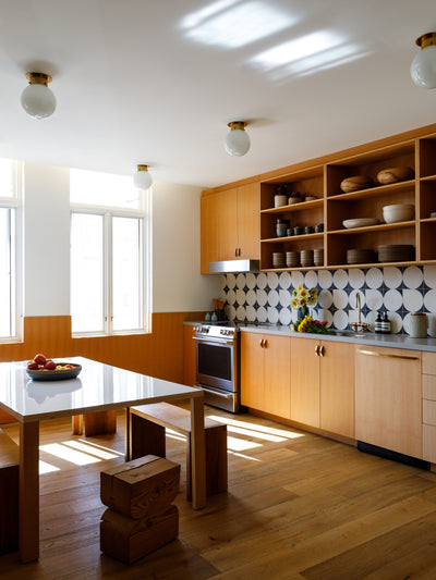 Commune Globe Flush Mounts adorn the ceiling of a sunlit kitchen with natural wood cabinets and flooring at the Commune Design Offices
