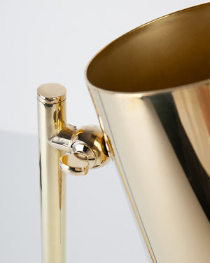 A detail of the top of can table lamp showing the two-way swivel and top of the cylindrical shade in a polished brass finish.
