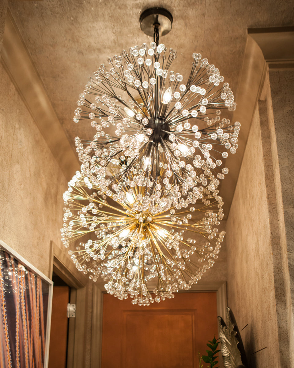 Two jewel like Dandelion 32 chandeliers with numerous stems radiating from a central cluster and finished with clear lucite balls. Each chandelier is lit and installed in a hallway with textured warm colored walls