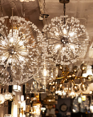 Dandelion Chandeliers lit and hanging amongst other lights at the Remains Lighting Showroom