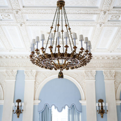 A restoration project including a large scale antique hand painted polychrome finish chandelier and sconces featuring fruit and berry details, by E.F. Caldwell and Co., installed at the Yale Club in New York City.